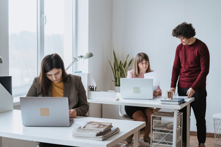 Colleagues working on laptops at shared desks in a bright modern office