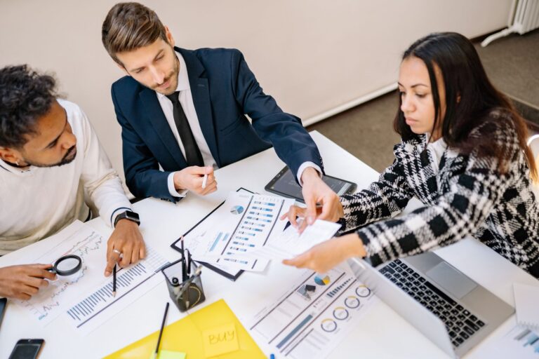 Business colleagues reviewing charts and documents together at a table in a bright office